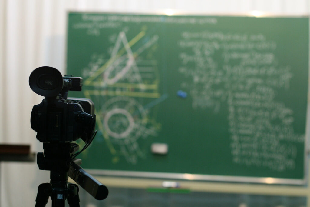 Camera pointing at a green chalkboard, streaming a maths lesson to an online audience.